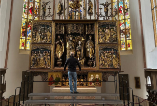 Eine Person steht mit dem Rücken zu uns auf dem neuen Podest und schaut auf den Hauptaltart