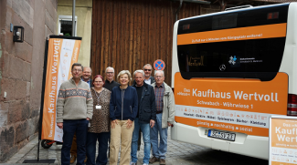 die Rückfläche des Busses mit der Werbund unt das Team um die Aktion steht dabei